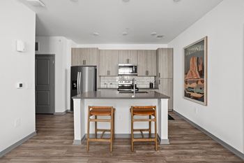 A kitchen with a bar stool and a fridge at The Maddox Luxury Apartments, Buckeye, 85326
